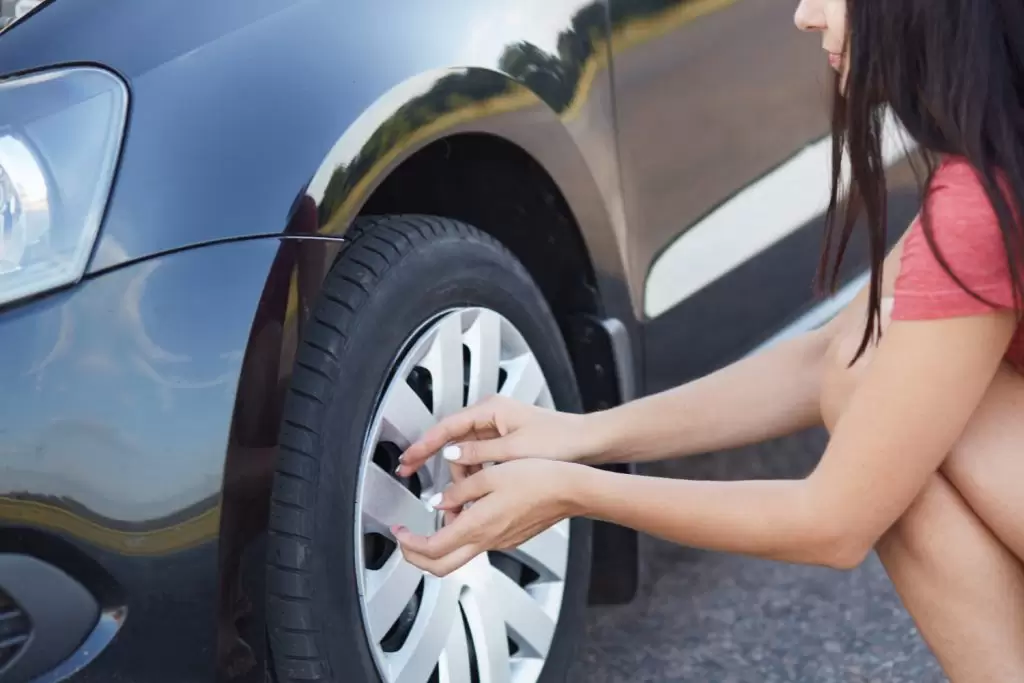 Mulher trocando pneu do carro