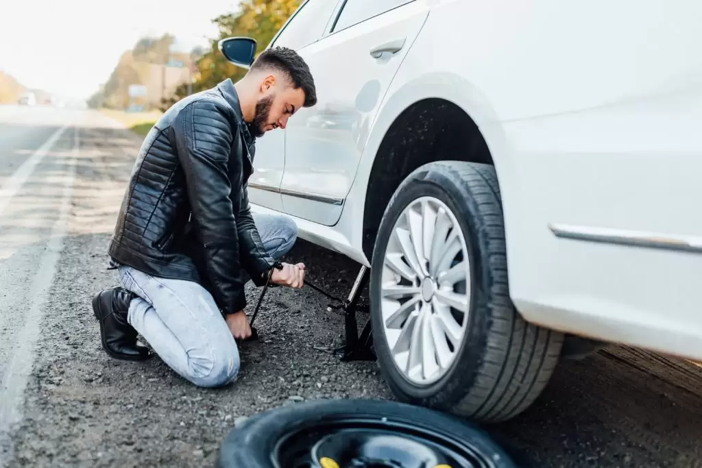 Homem trocando pneu do carro