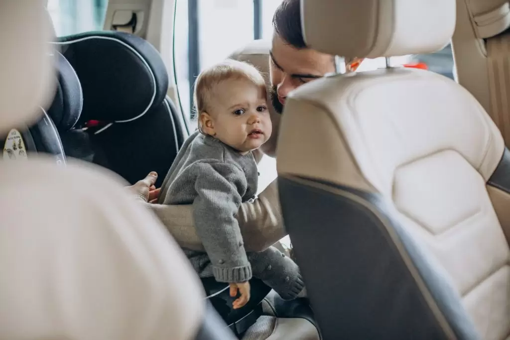 escolher um bebê conforto: pai colocando bebê no carro