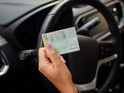 Com quantos pontos perde a cnh: pessoa segurando cnh dentro do carro.
