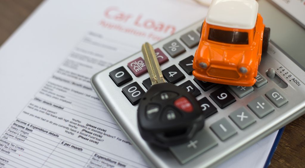 chave de carro e miniatura de carro encima de uma calculadora