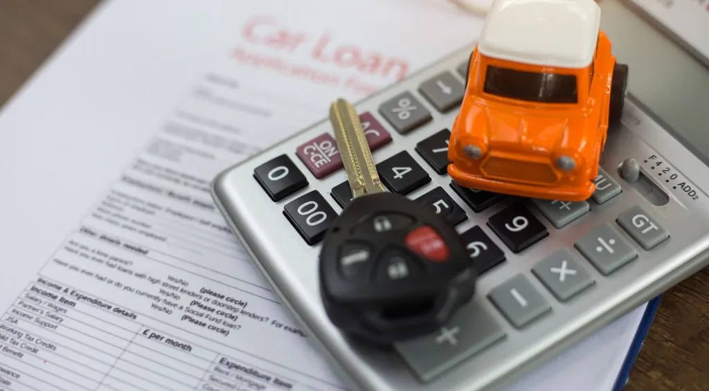 chave de carro e miniatura de carro encima de uma calculadora